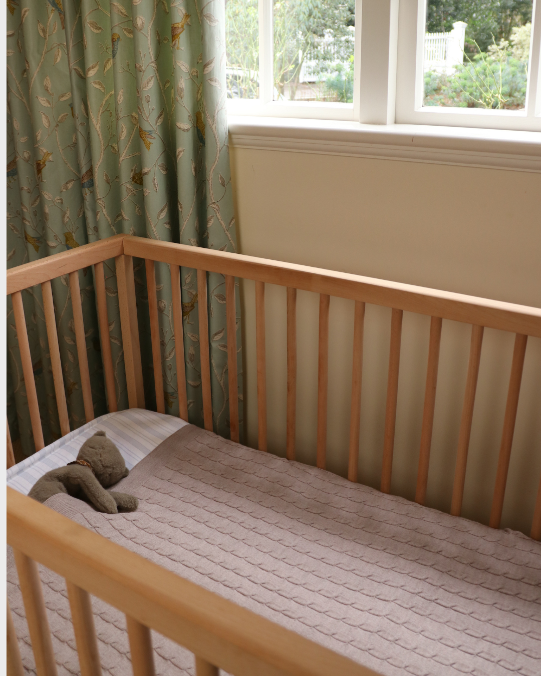 Merino baby blanket in a crib with wooden rails, showcasing soft, breathable wool.