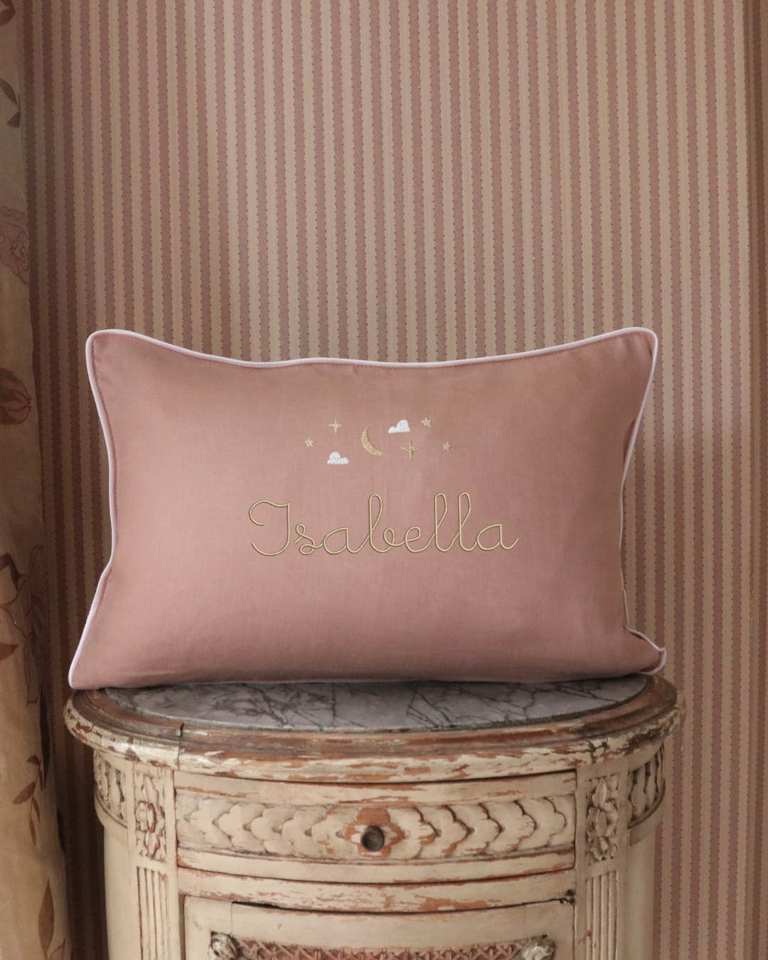 Moon and Stars Cushion with embroidered name, hand-stitched moon and stars design on soft pink fabric with white piping.