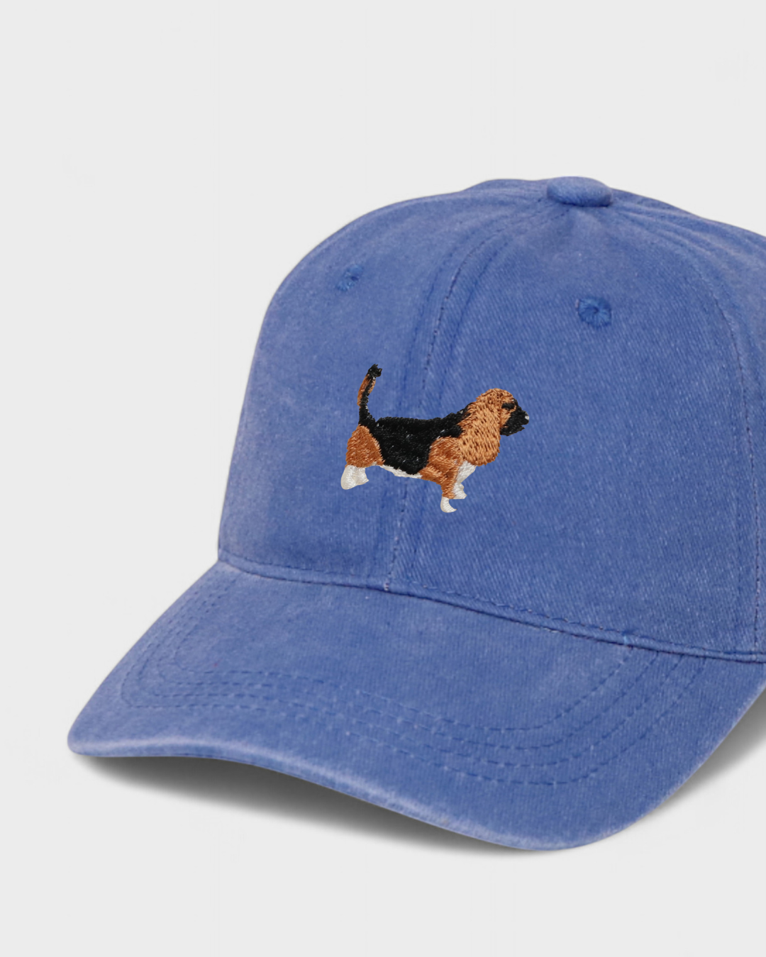 Blue baseball cap with embroidered hand-drawn Basset Hound design, personalised embroidery option on the back, made of 100% washed cotton.