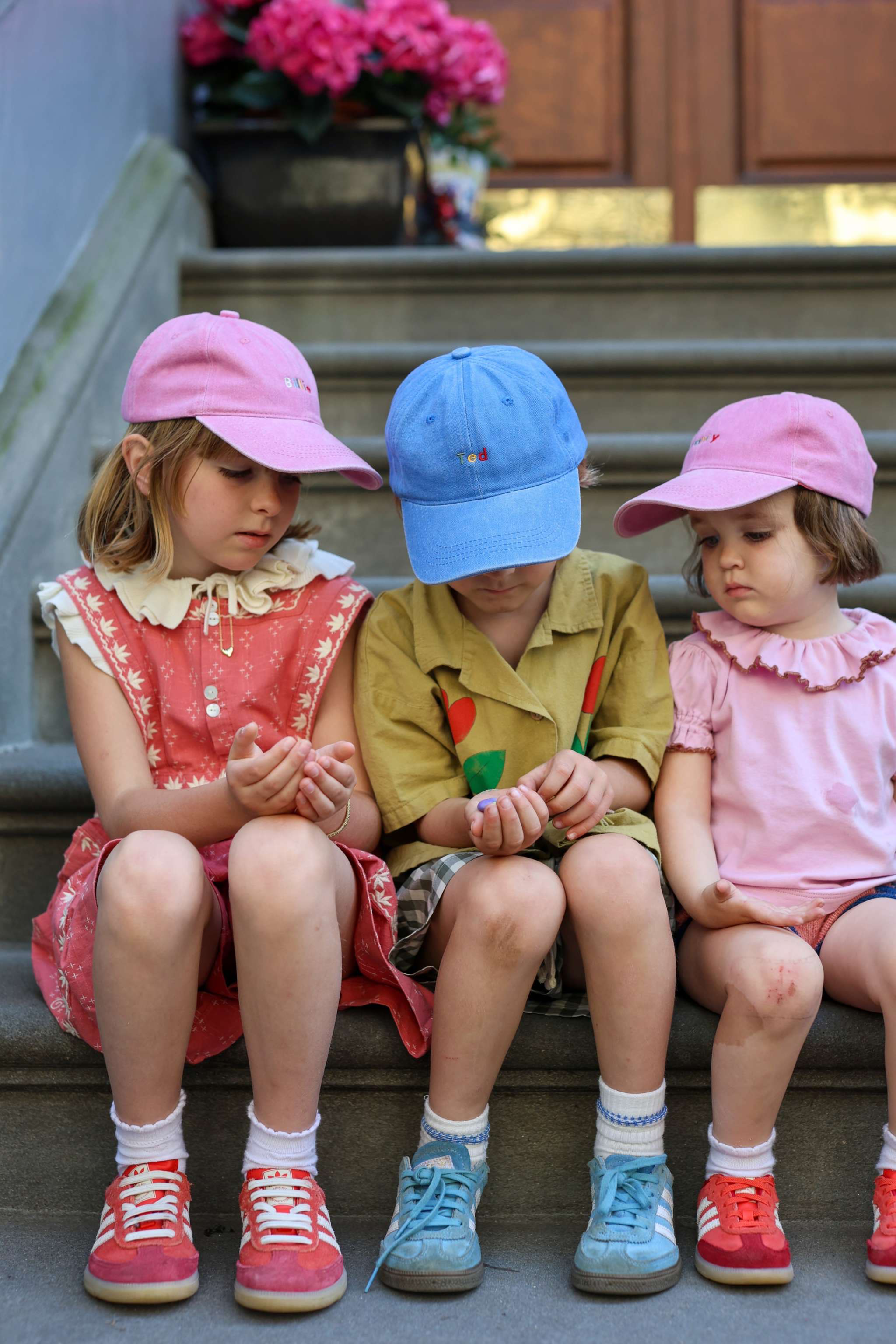 Children wearing personalised hats with multi-coloured text, featuring classic baseball fit and made of 100% washed cotton.