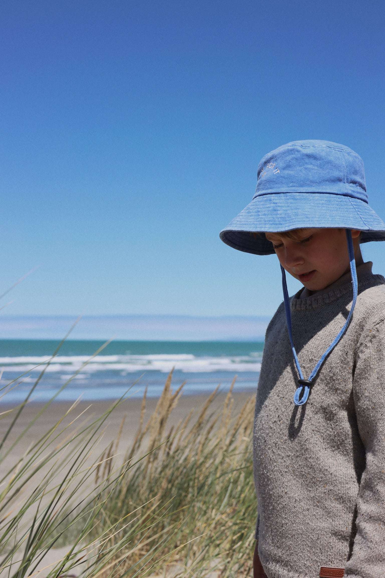 Customised bucket hat on a child at the beach, made of 100% washed cotton.