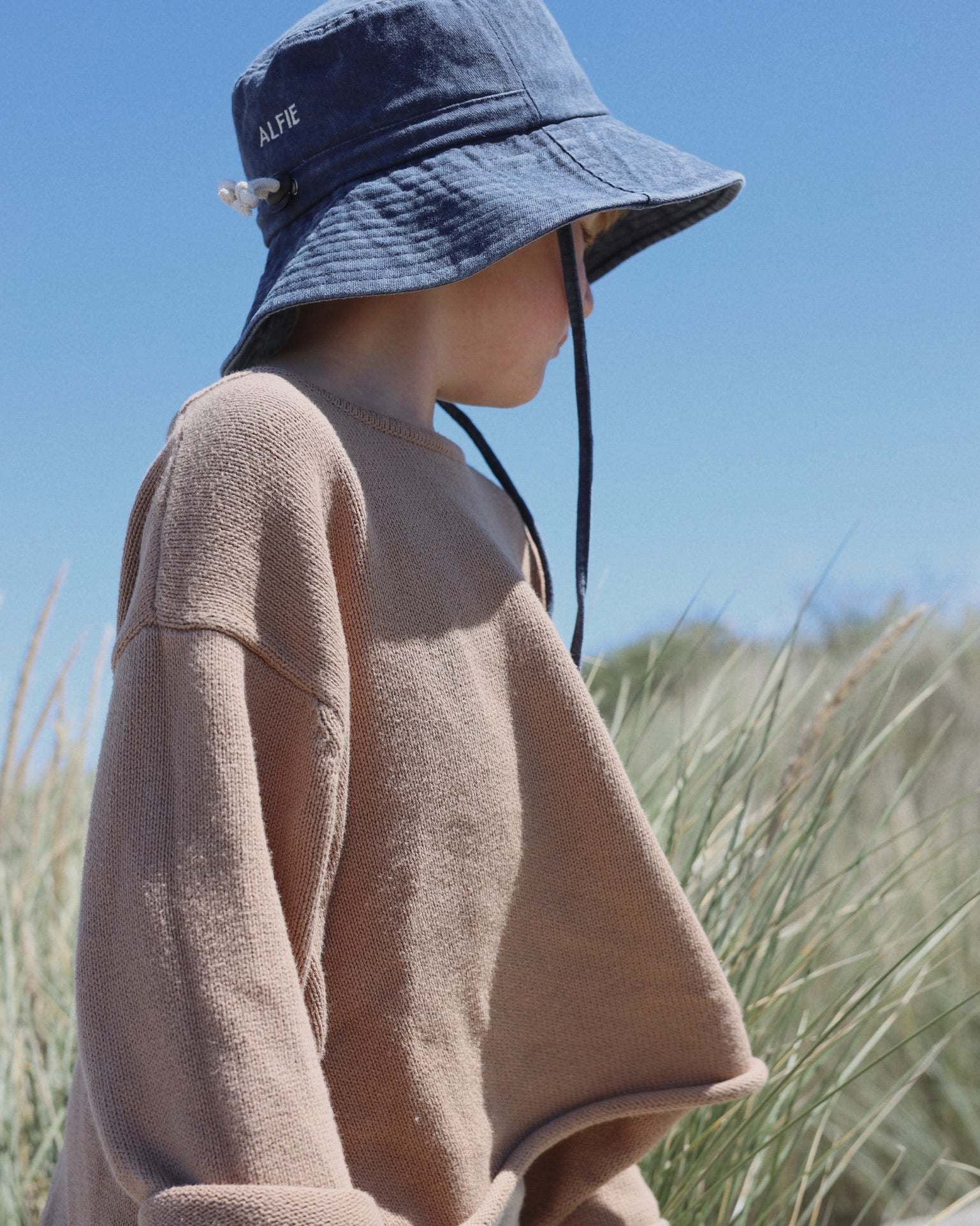 Child wearing Digger personalised bucket hat outdoors.
