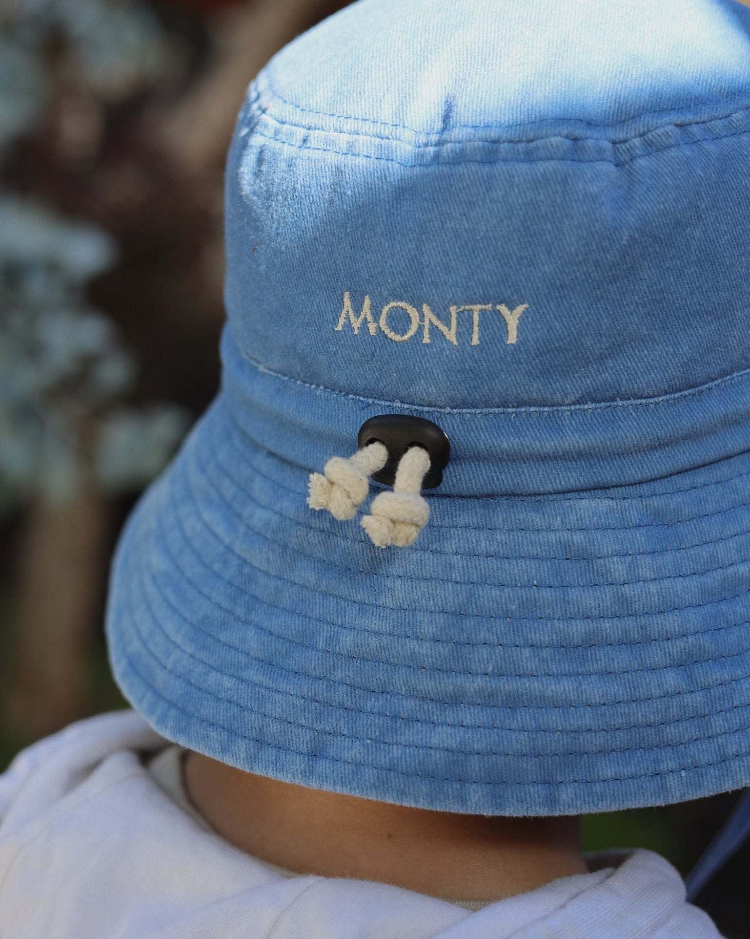 Customised blue bucket hat with embroidered text, made of 100% washed cotton for kids.