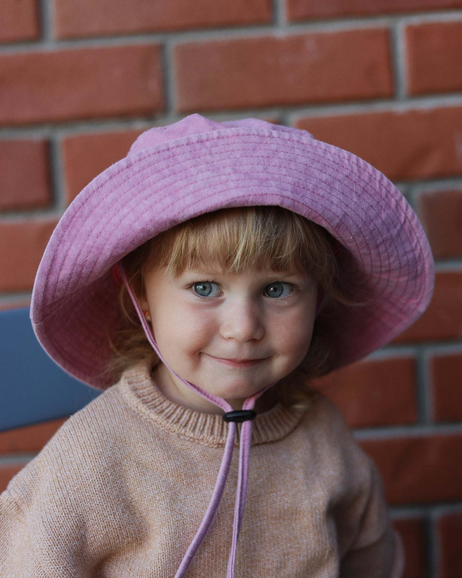 Child wearing pink Ferrari personalised bucket hat made of soft washed cotton, designed for ages 2-6 years