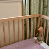 Merino baby blanket with embroidered name in a crib.