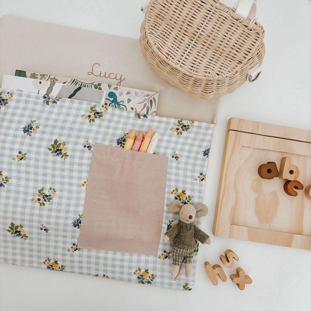 Personalised chair bag with floral gingham design, children's name embroidery, and stationery, promoting organized learning.