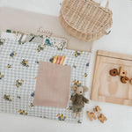 Personalised chair bag with floral gingham design, children's name embroidery, and stationery, promoting organized learning.