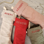 Set of personalized linen Christmas stockings with Nordic cross stitch names in red embroidery threads