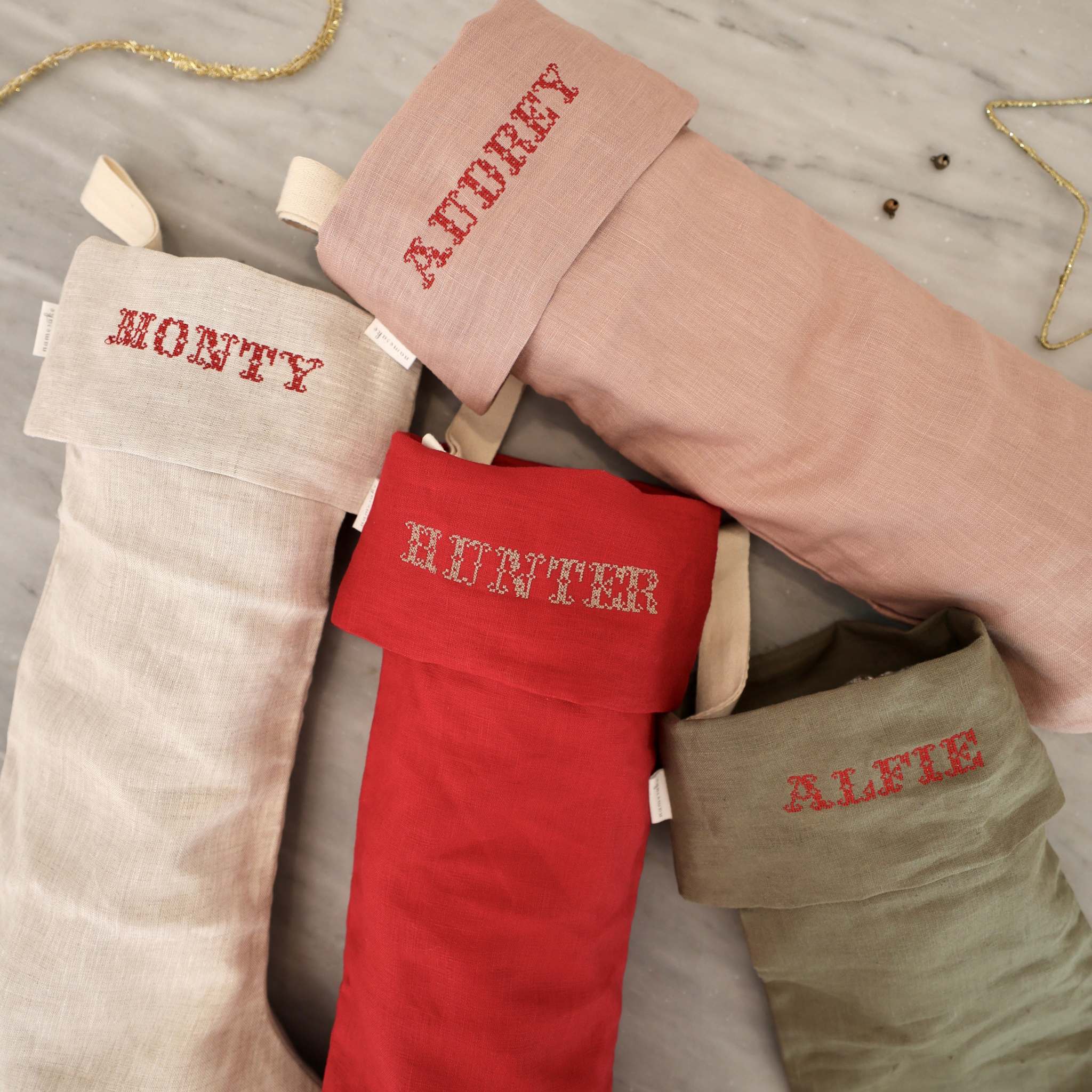 Set of personalized linen Christmas stockings with Nordic cross stitch names in red embroidery threads