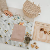 Personalised floral gingham chair bag with crayons and toys on a learning table.
