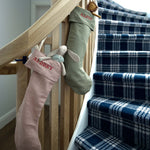 Personalized linen Christmas stockings with vintage Nordic cross stitch embroidery hanging on staircase railing