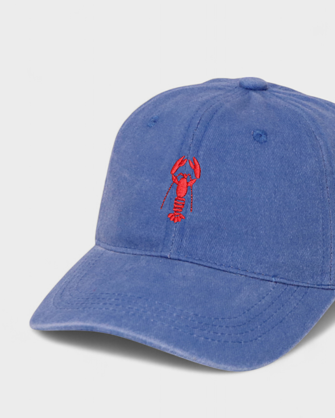 Blue washed cotton personalised hat featuring hand-embroidered red lobster design on front with customisable embroidery on the back.