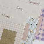 Personalised chair bags in floral gingham design, embroidered with children's names.