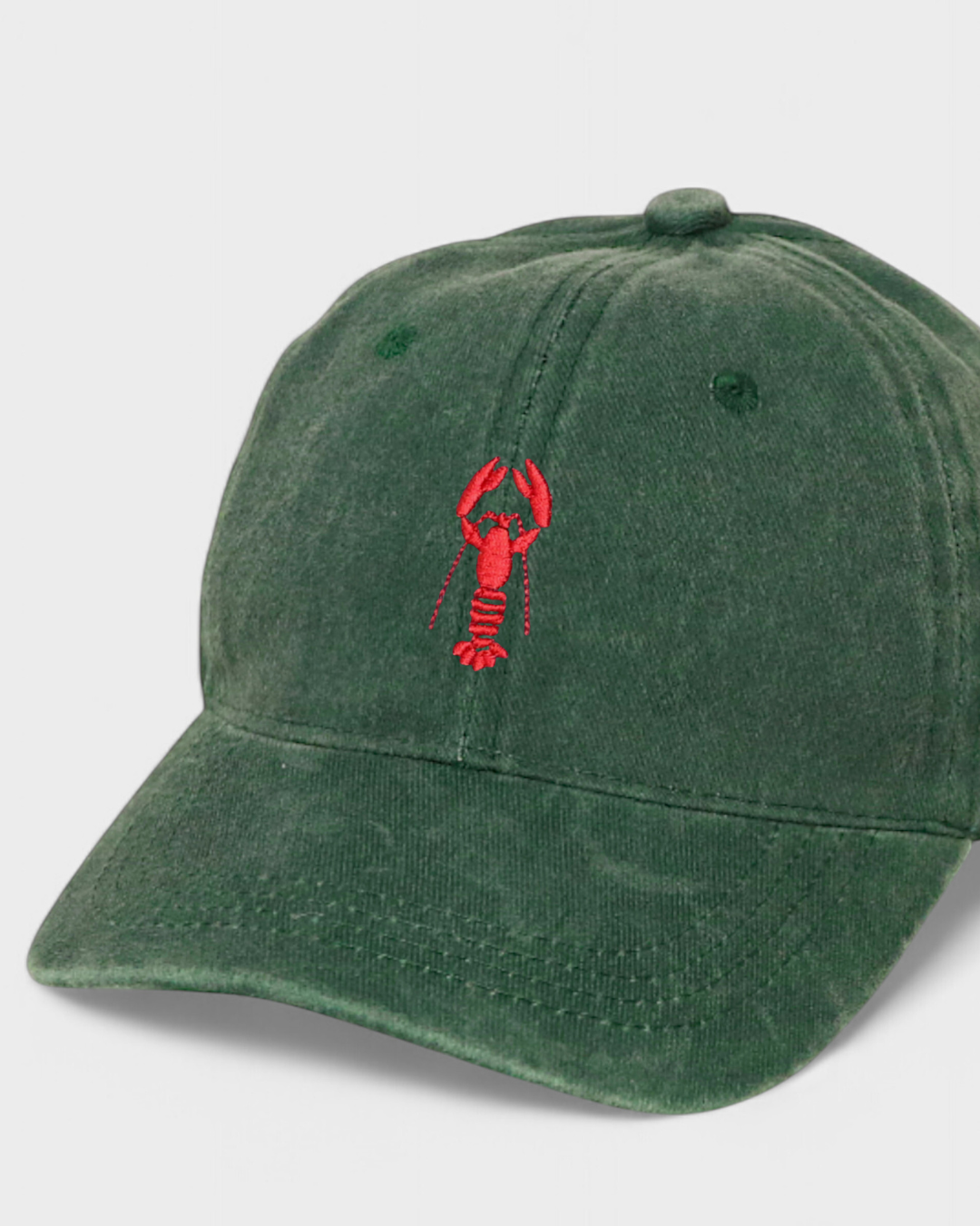 Green personalised hat with red hand-drawn lobster embroidery on front, made of 100% washed cotton, classic baseball fit.