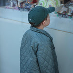Tennis personalised hat with embroidery design, worn by a child in a stylish quilted jacket.