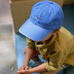 Blue personalised hat with multi-coloured text on a child outdoors.