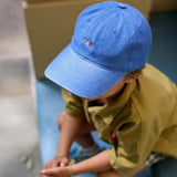 Blue personalised hat with multi-coloured text on a child outdoors.