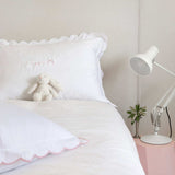 Organic cotton pillowcase with white scalloped edge on a bed.