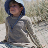 Child wearing a blue customised bucket hat made of 100% washed cotton at the beach.