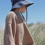 Child wearing a personalised navy blue cotton bucket hat embroidered with the name Alfie outdoors in nature