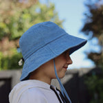 Customised blue bucket hat on a child made of 100% washed cotton, individually embroidered in Auckland.